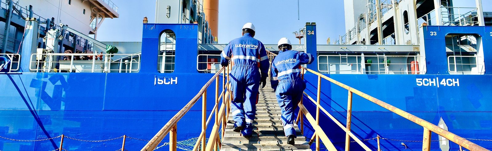 Dos técnicos de Lubmarine suben por la escala de un buque de carga